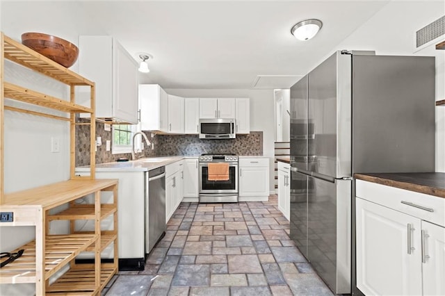 331 E 100th Ter, Kansas City, MO 64114 - kitchen featuring stainless steel appliances, tasteful backsplash, white cabinetry, and light stone finish floors