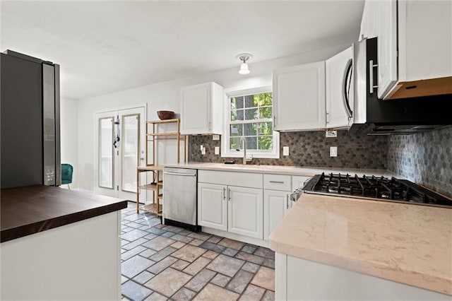331 E 100th Ter, Kansas City, MO 64114 - kitchen with stainless steel dishwasher, decorative backsplash, white cabinets, and stove