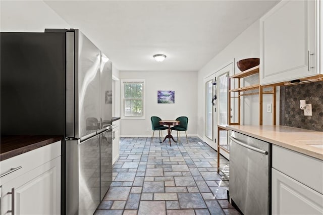 331 E 100th Ter, Kansas City, MO 64114 - kitchen with appliances with stainless steel finishes, white cabinetry, stone tile flooring, open shelves, and decorative backsplash