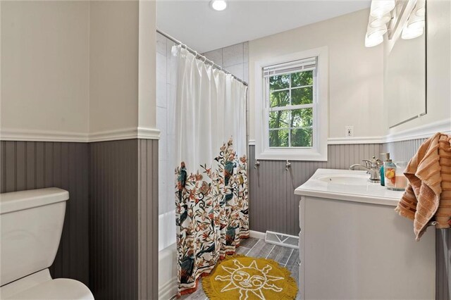 331 E 100th Ter, Kansas City, MO 64114 - bathroom featuring wainscoting, vanity, wood finished floors, shower / tub combo with curtain, and recessed lighting