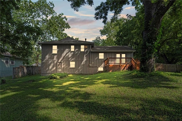 331 E 100th Ter, Kansas City, MO 64114 - back of property at dusk with a fenced backyard, board and batten siding, a deck, and stairway