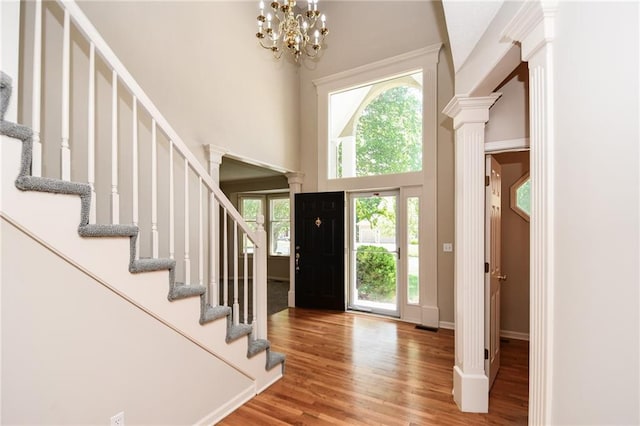 11912 W 132nd St, Overland Park, KS 66213 - entryway featuring ornate columns, stairs, a high ceiling, wood finished floors, and a chandelier