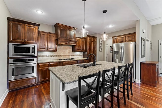 4890 NW Linder Ln, Riverside, MO 64150 - kitchen with stainless steel appliances, dark wood-type flooring, tasteful backsplash, a kitchen bar, and a center island with sink