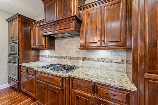 4890 NW Linder Ln, Riverside, MO 64150 - kitchen featuring stainless steel appliances, wood finished floors, tasteful backsplash, and light stone countertops