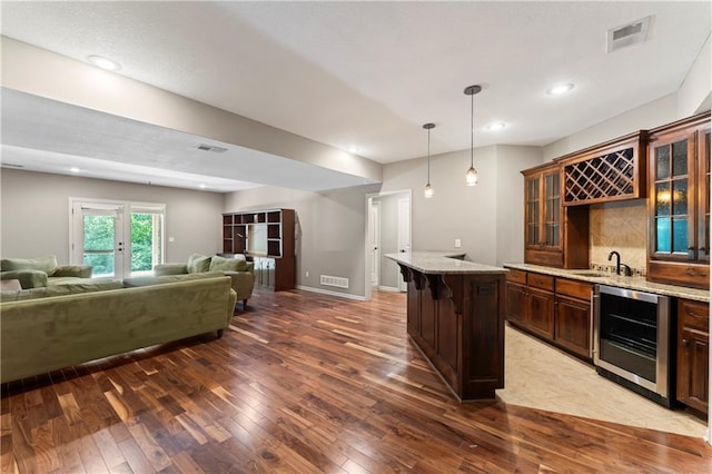4890 NW Linder Ln, Riverside, MO 64150 - indoor wet bar with wine cooler, dark wood finished floors, decorative light fixtures, decorative backsplash, and recessed lighting