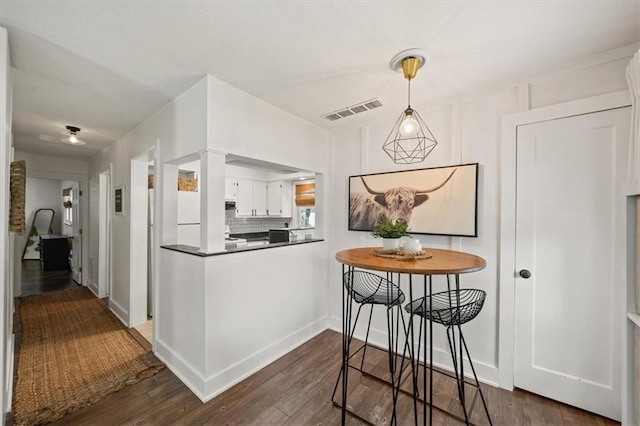 236 W Park St, Gardner, KS 66030 - kitchen with dark wood-type flooring, white cabinets, dark countertops, pendant lighting, and backsplash
