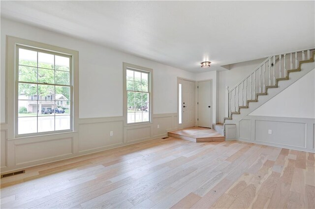 16117 W 125th Ter, Olathe, KS 66062 - foyer entrance featuring light wood-style floors, wainscoting, stairway, and a decorative wall