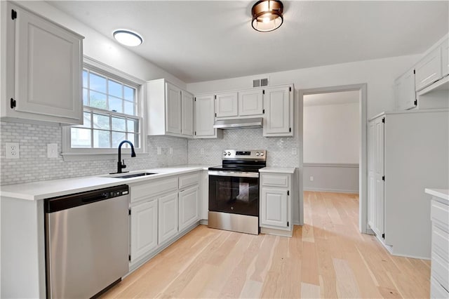 16117 W 125th Ter, Olathe, KS 66062 - kitchen with appliances with stainless steel finishes, under cabinet range hood, light wood-type flooring, light countertops, and tasteful backsplash
