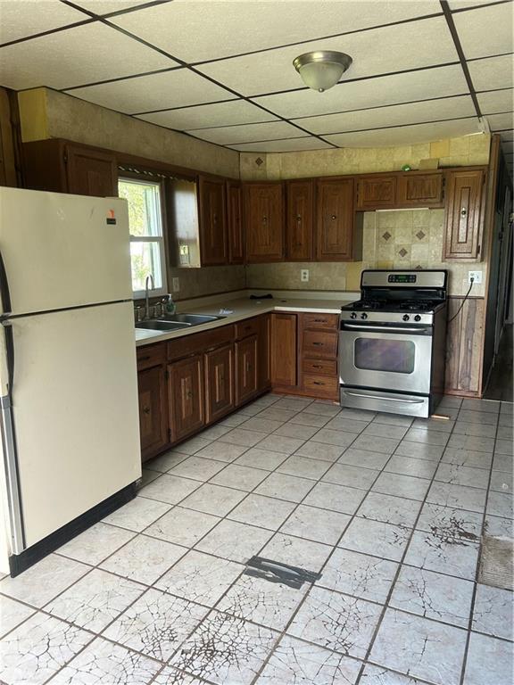 10 Platte St, Dearborn, MO 64439 - kitchen with freestanding refrigerator, a paneled ceiling, stainless steel gas range, and light countertops