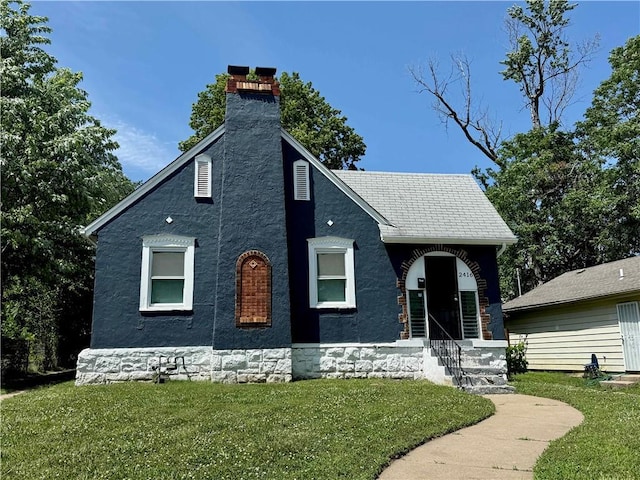 2416 E 70th St, Kansas City, MO 64132 - tudor-style house featuring a front lawn, a chimney, entry steps, and stucco siding