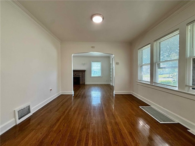 2416 E 70th St, Kansas City, MO 64132 - unfurnished living room featuring arched walkways, a brick fireplace, wood-type flooring, and crown molding