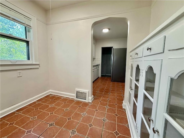 2416 E 70th St, Kansas City, MO 64132 - spare room featuring arched walkways and dark tile patterned floors