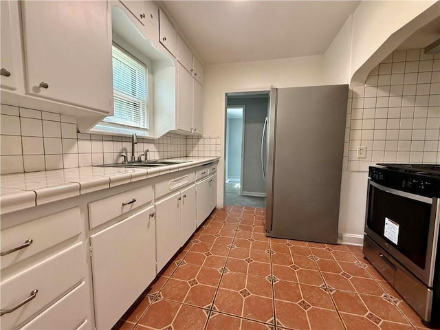 2416 E 70th St, Kansas City, MO 64132 - kitchen with stainless steel appliances, tile counters, and white cabinetry