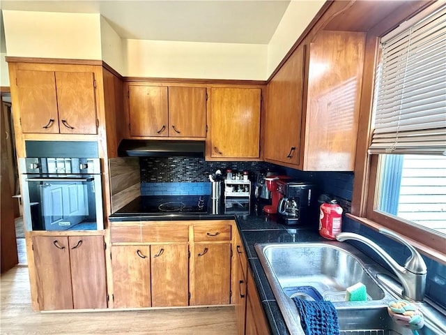 226 Mckenzie St, Barnard, MO 64423 - kitchen featuring oven, under cabinet range hood, dark countertops, brown cabinets, and black electric cooktop