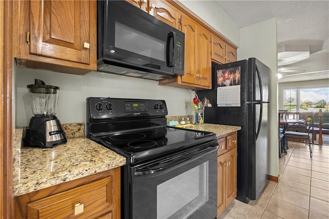 3602 S Sweeney Rd, Grain Valley, MO 64029 - kitchen featuring black appliances, brown cabinetry, light tile patterned floors, and light stone counters