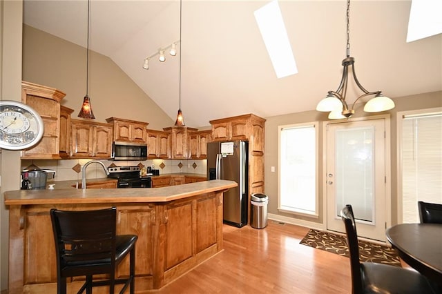 19617 Harbor Dr, Smithville, MO 64089 - kitchen featuring stainless steel appliances, backsplash, a skylight, light wood-type flooring, and a peninsula