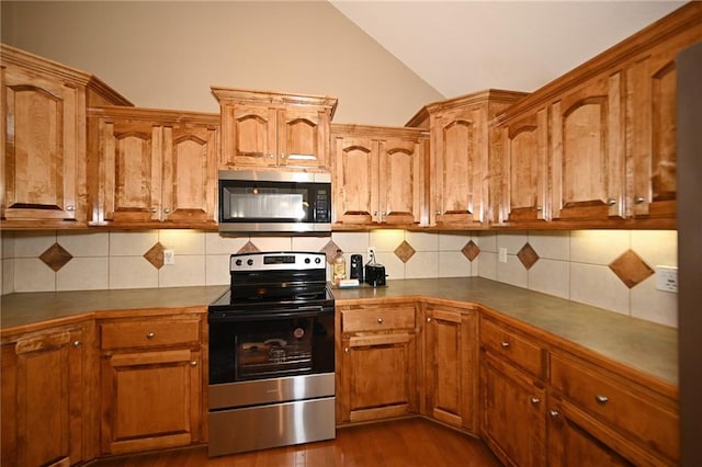 19617 Harbor Dr, Smithville, MO 64089 - kitchen featuring stainless steel appliances, vaulted ceiling, decorative backsplash, dark wood-style flooring, and dark countertops