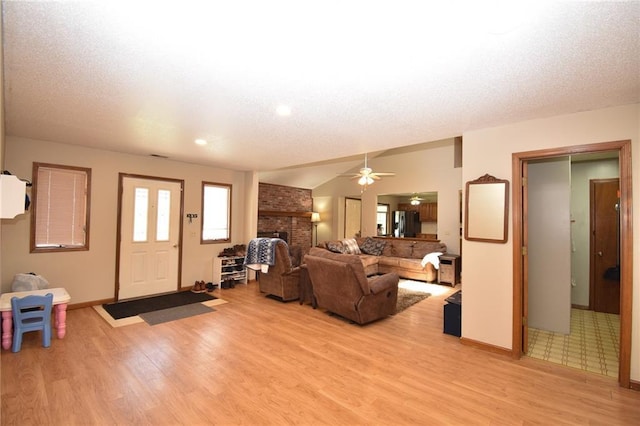 211 Southside Ct, Excelsior Springs, MO 64024 - living room with a brick fireplace, light wood-style floors, ceiling fan, and a textured ceiling