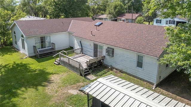 211 Southside Ct, Excelsior Springs, MO 64024 - back of property with a shingled roof, a deck, a lawn, and view of scattered trees