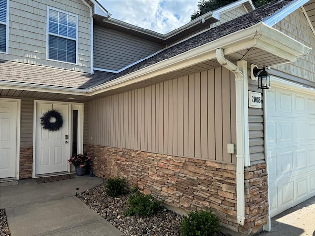 21086 Millridge St, Spring Hill, KS 66083 - property entrance with a garage, stone siding, roof with shingles, and board and batten siding