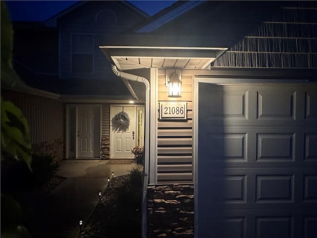 21086 Millridge St, Spring Hill, KS 66083 - exterior entry at twilight featuring a balcony, a garage, and stone siding