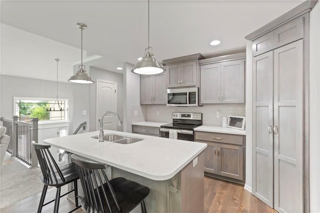 20335 W 220th Ter, Spring Hill, KS 66083 - kitchen featuring stainless steel appliances, light countertops, an island with sink, wood finished floors, and gray cabinetry
