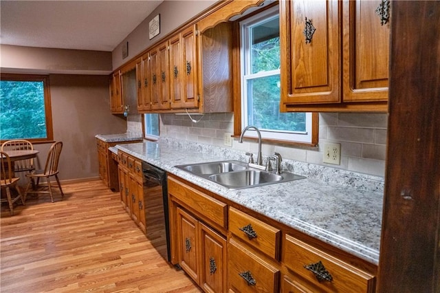 2421 Elephant Trl, Saint Joseph, MO 64506 - kitchen featuring black dishwasher, brown cabinetry, light wood finished floors, and tasteful backsplash