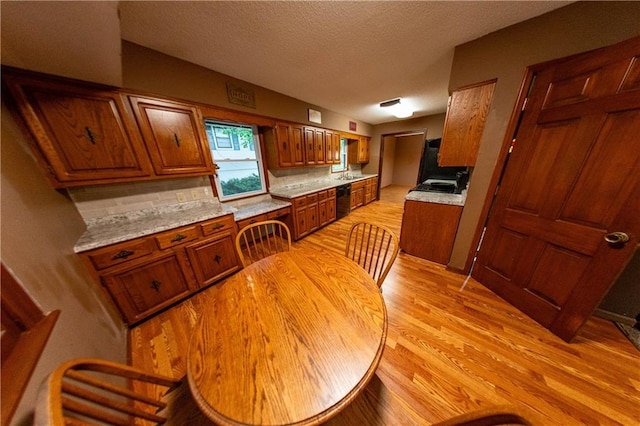 2421 Elephant Trl, Saint Joseph, MO 64506 - kitchen with brown cabinets, light countertops, light wood finished floors, dishwasher, and a textured ceiling