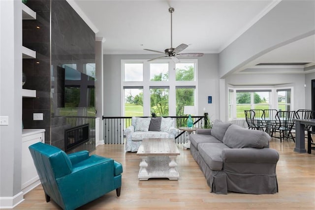 14423 N 145th St, Basehor, KS 66007 - living room featuring ornamental molding, ceiling fan, a fireplace, light wood-style floors, and arched walkways
