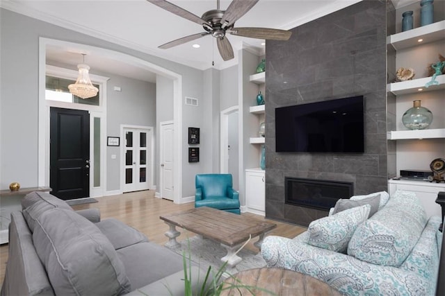 14423 N 145th St, Basehor, KS 66007 - living area featuring built in features, light wood-style floors, ornamental molding, a tiled fireplace, and a ceiling fan