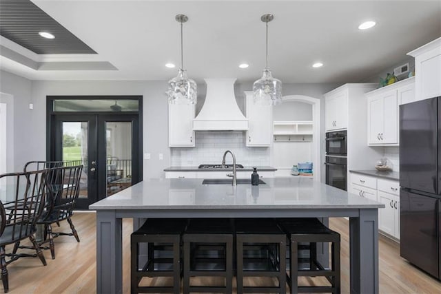 14423 N 145th St, Basehor, KS 66007 - kitchen featuring custom exhaust hood, black appliances, decorative backsplash, light wood-style flooring, and recessed lighting