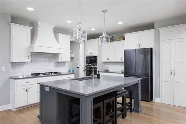 14423 N 145th St, Basehor, KS 66007 - kitchen featuring freestanding refrigerator, custom range hood, stainless steel gas cooktop, light wood-type flooring, and white cabinetry