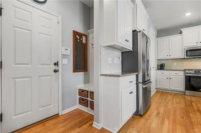 23852 W 124th Ct, Olathe, KS 66061 - kitchen with appliances with stainless steel finishes, light wood-style floors, white cabinets, backsplash, and stone counters
