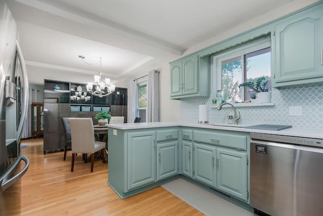 1702 Aspen Ln, Excelsior Springs, MO 64024 - kitchen with appliances with stainless steel finishes, light countertops, a peninsula, and a chandelier