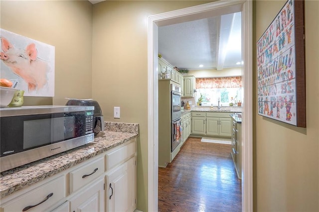 12432 Lamar Ave, Overland Park, KS 66209 - kitchen featuring stainless steel appliances, wood finished floors, and light stone counters