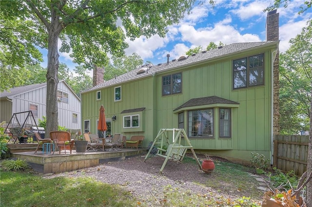 12432 Lamar Ave, Overland Park, KS 66209 - rear view of property with a chimney, a deck, board and batten siding, and a shingled roof