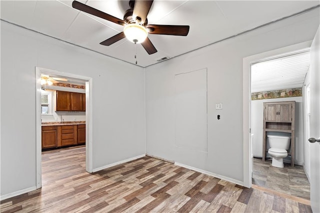 921 E Vine St, Rich Hill, MO 64779 - unfurnished bedroom featuring light wood-style flooring, connected bathroom, and a ceiling fan