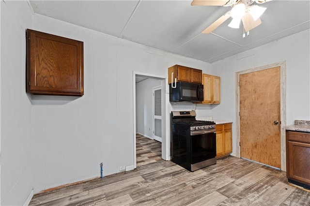 921 E Vine St, Rich Hill, MO 64779 - kitchen featuring stainless steel gas range oven, black microwave, light wood-type flooring, and ceiling fan