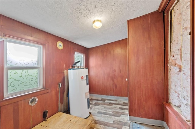921 E Vine St, Rich Hill, MO 64779 - laundry room featuring water heater, a textured ceiling, wood finished floors, and wooden walls