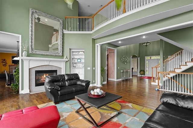 14409 Grandview St, Overland Park, KS 66221 - living room featuring wood finished floors, a glass covered fireplace, stairway, a towering ceiling, and arched walkways