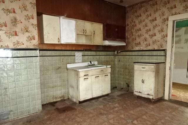 426 Pottawatomie St, Leavenworth, KS 66048 - kitchen featuring wallpapered walls, a wainscoted wall, ventilation hood, dark floors, and light countertops