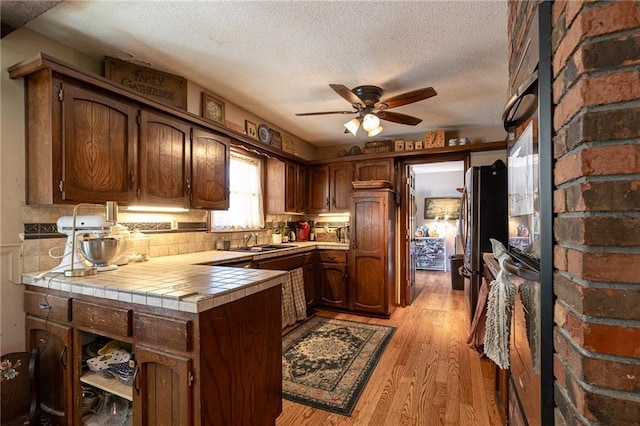 25421 Marel Rd, Excelsior Springs, MO 64024 - kitchen featuring tile counters, ceiling fan, a textured ceiling, light wood-type flooring, and freestanding refrigerator