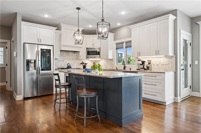 16420 Lucille St, Overland Park, KS 66221 - kitchen featuring appliances with stainless steel finishes, a center island, a breakfast bar area, white cabinetry, and dark wood-style flooring