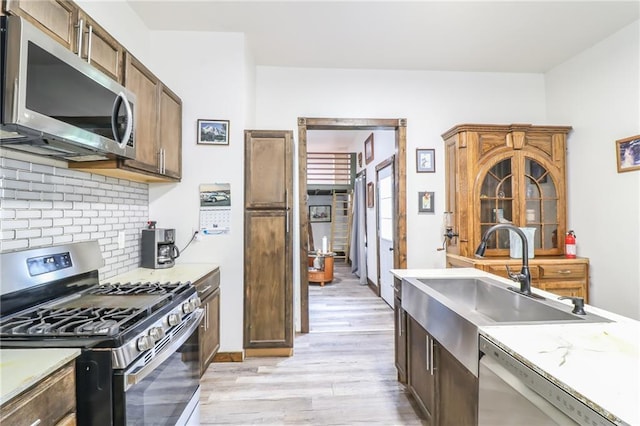 600 W Chestnut St, Holden, MO 64040 - kitchen featuring appliances with stainless steel finishes, light wood-style flooring, tasteful backsplash, and light countertops