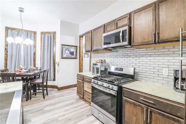 600 W Chestnut St, Holden, MO 64040 - kitchen featuring stainless steel appliances, tasteful backsplash, light wood-type flooring, light stone countertops, and pendant lighting