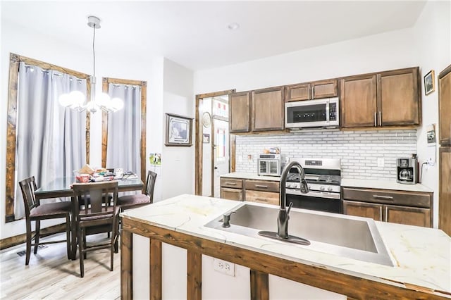 600 W Chestnut St, Holden, MO 64040 - kitchen with stainless steel appliances, a chandelier, tasteful backsplash, pendant lighting, and light wood finished floors