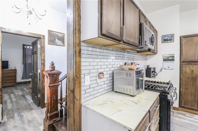 600 W Chestnut St, Holden, MO 64040 - kitchen with stainless steel appliances, light wood-type flooring, backsplash, and a chandelier