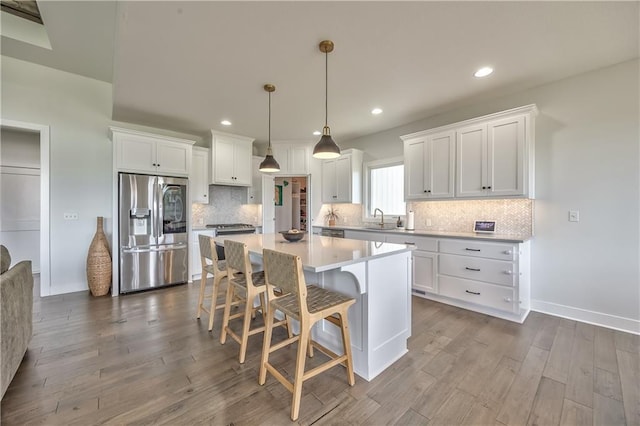 24976 W 87th St, Lenexa, KS 66227 - kitchen with stainless steel refrigerator with ice dispenser, white cabinets, a kitchen bar, a kitchen island, and dark wood-style floors