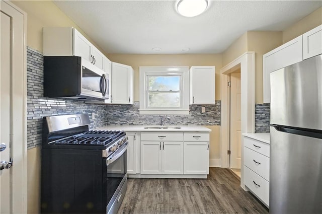 1962 N 28th St, Kansas City, KS 66104 - kitchen featuring appliances with stainless steel finishes, dark wood-type flooring, light countertops, white cabinets, and a textured ceiling