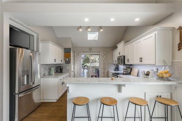 8103 NE 111th Ter, Kansas City, MO 64157 - kitchen with appliances with stainless steel finishes, lofted ceiling, light countertops, a peninsula, and white cabinets